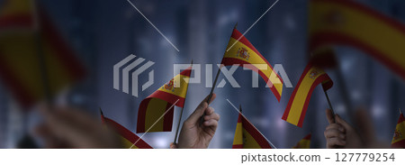 Spain flags in their hands on a blurred urban background 127779254
