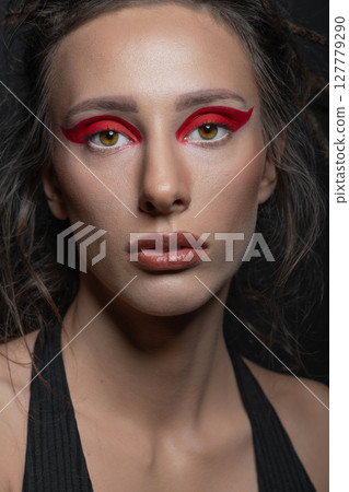 Studio portrait of beautiful woman with red eye shadows and dreadlocks 127779290