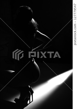 Naked woman body dark silhouette illuminated with light 127779547
