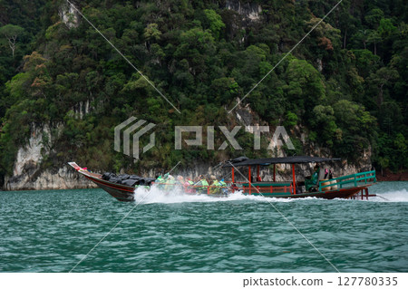 Suratthani, Thailand - February 23, 2028: longtail boat on Cheow Lan lake at Khao Sok national park. Thailand Suratthani, Thailand - February 23, 2028: longtail boat on Cheow Lan lake at Khao Sok national park. Thailand 127780335