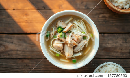 Delicious chicken noodle soup with fresh green onions and rice on a wooden table. Delicious chicken noodle soup with fresh green onions and rice on a wooden table. 127780860