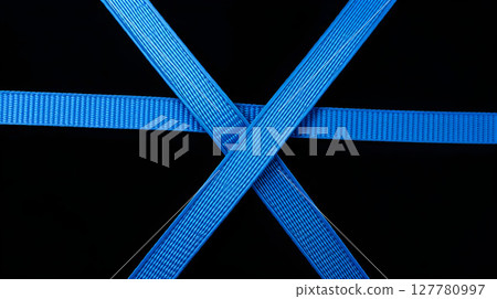 Abstract composition featuring overlapping blue straps, geometric shapes, and a striking black background 127780997