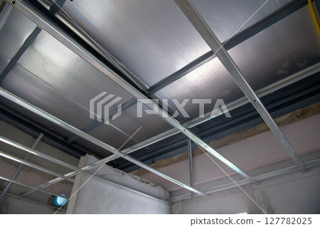 Meticulous interior renovation shows an aluminium ceiling framework with electrical wiring. detailed installation is part of commercial building project for new office 127782025