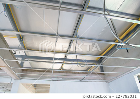 Interior renovation project showing installation of new suspended ceiling. aluminium framework holds electrical wiring in view of hopeful construction progress Interior renovation project showing installation of new suspended ceiling. aluminium framework holds electrical wiring in view of hopeful construction progress 127782031