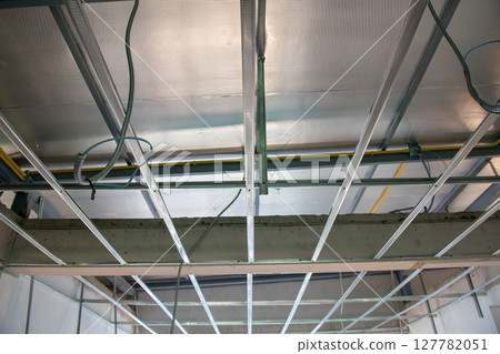 Unfinished interior renovation project showing electrical wiring installation within metal ceiling framework. complex aluminium grid shows detail of construction work Unfinished interior renovation project showing electrical wiring installation within metal ceiling framework. complex aluminium grid shows detail of construction work 127782051