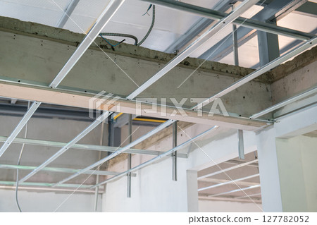 Interior renovation in progress shows careful installation of an aluminium ceiling framework with complex electrical wiring for modern residential build project Interior renovation in progress shows careful installation of an aluminium ceiling framework with complex electrical wiring for modern residential build project 127782052
