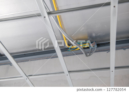 Interior renovation showing electrical wiring and aluminium ceiling framework installation. meticulous construction highlights grid and junction box for new building 127782054
