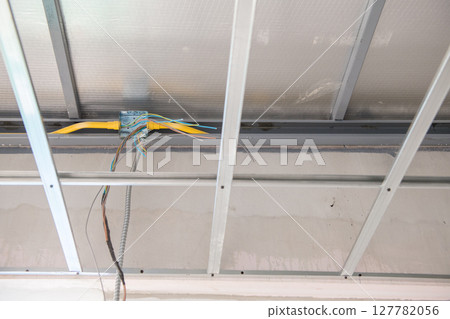 Close up of an aluminium ceiling framework with exposed electrical wiring. An interior view showing raw installation and renovation process of suspended structure 127782056
