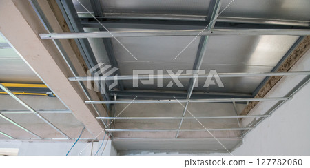 Interior renovation showing electrical wiring and aluminium ceiling framework. installation is part of major remodeling project leaving raw industrial feeling of being under construction Interior renovation showing electrical wiring and aluminium ceiling framework. installation is part of major remodeling project leaving raw industrial feeling of being under construction 127782060
