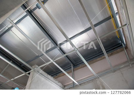 Aluminium ceiling framework during interior renovation shows meticulous electrical wiring installation. grid system supports thermal insulation for modern building update 127782066
