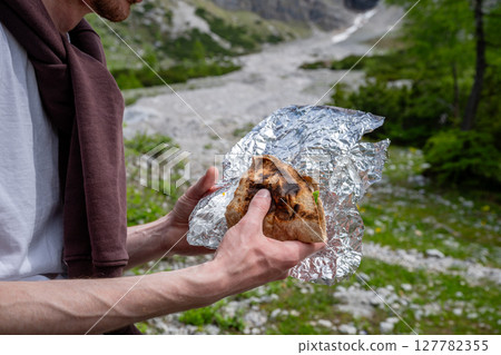 Hands holding grilled flatbreads with alpine mountains in the background 127782355