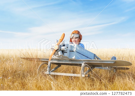 Little boy is playing the plane. 127782473