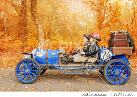 Young racer and mechanic riding an old race car 127783103