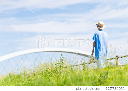A young woman walking while wearing a straw hat Lifestyle image 127784031
