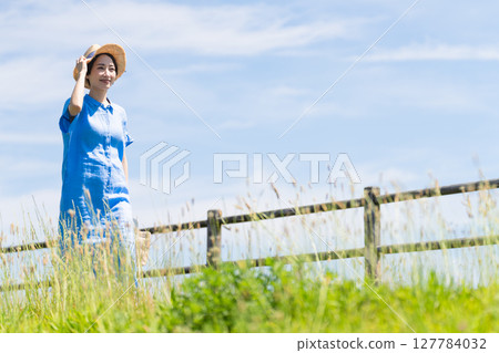 A young woman walking while wearing a straw hat Lifestyle image 127784032