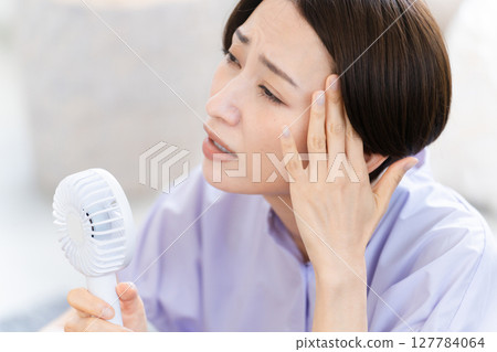 Young woman using a hand fan Lifestyle image 127784064