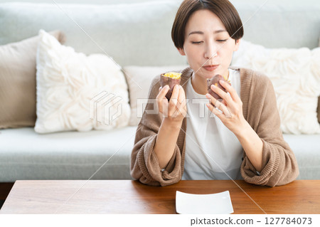 Young woman eating roasted sweet potato lifestyle image 127784073