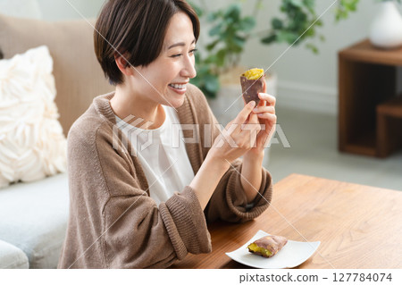 Young woman eating roasted sweet potato lifestyle image 127784074