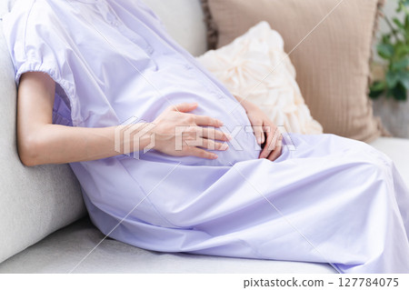 Pregnant woman relaxing on the sofa lifestyle image 127784075