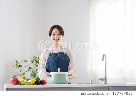 穿著圍裙煮飯的年輕女子 — 生活方式形象 穿著圍裙煮飯的年輕女子 — 生活方式形象 127784082