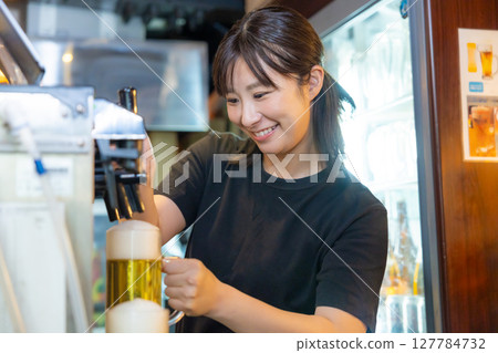 居酒屋啤酒服務生女工作人員倒啤酒 居酒屋啤酒服務生女工作人員倒啤酒 127784732