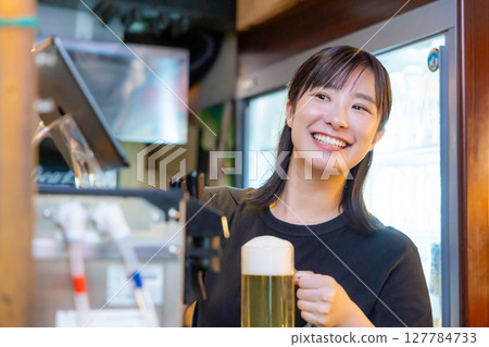 Izakaya beer server female staff pouring beer 127784733