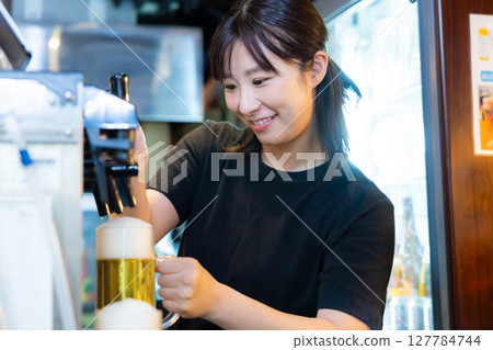 Izakaya beer server female staff pouring beer Izakaya beer server female staff pouring beer 127784744