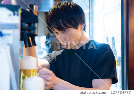 Izakaya beer server male staff pouring beer 127784777