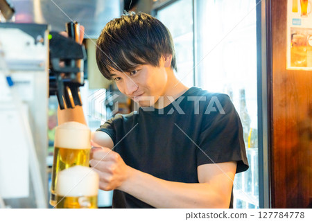 Izakaya beer server male staff pouring beer 127784778