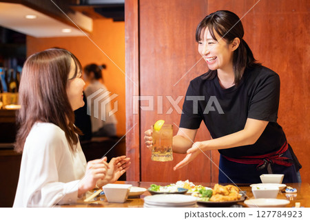 Izakaya: Female staff serving drinks to customers Izakaya: Female staff serving drinks to customers 127784923