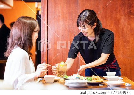 Izakaya: Female staff serving drinks to customers 127784924
