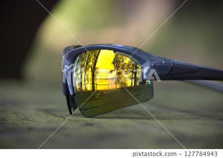 Sunglasses reflecting a beautiful golden sunset over a tranquil lake scene. Sunglasses reflecting a beautiful golden sunset over a tranquil lake scene. 127784943
