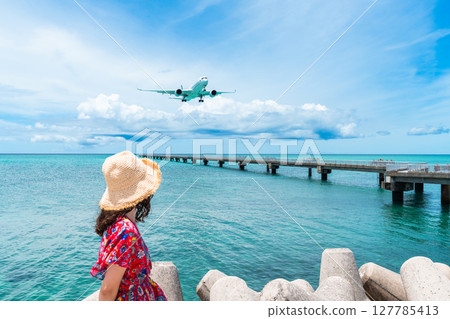 17 End: A young woman and a passenger plane passing overhead 127785413