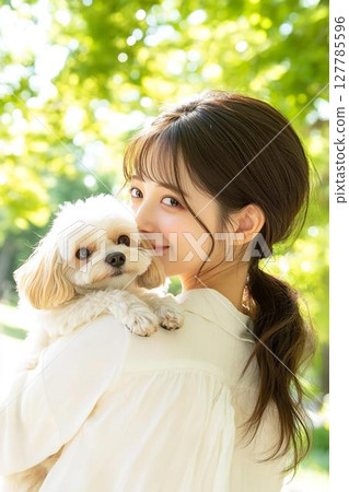 在柔和的陽光下,一位女士抱著一隻白狗 在柔和的陽光下,一位女士抱著一隻白狗 127785596