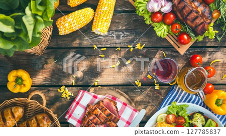 A picnic table features grilled meats, corn on the cob, and fresh salads in the sunny atmosphere. A picnic table features grilled meats, corn on the cob, and fresh salads in the sunny atmosphere. 127785837