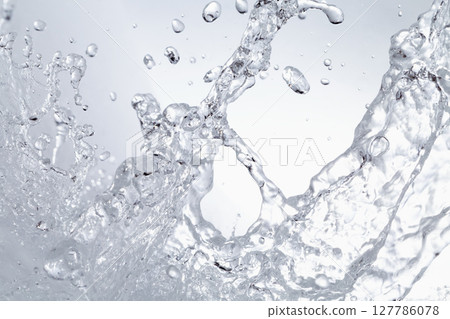 水濺在灰色的背景上。 127786078