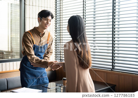 Entrepreneurial Engagement. Young professionals shaking hands in a modern workspace. 127786183
