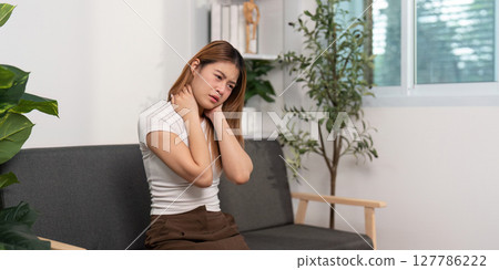 Neck Pain Awareness. Young woman experiencing neck discomfort while sitting. Neck Pain Awareness. Young woman experiencing neck discomfort while sitting. 127786222