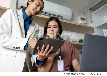 Exploring Technology in the Office. Businesswomen reviewing digital tools in a modern workspace. Exploring Technology in the Office. Businesswomen reviewing digital tools in a modern workspace. 127786336
