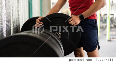 Weightlifting and Fitness. Man adjusting weights in the gym, focusing on strength training. Weightlifting and Fitness. Man adjusting weights in the gym, focusing on strength training. 127786411