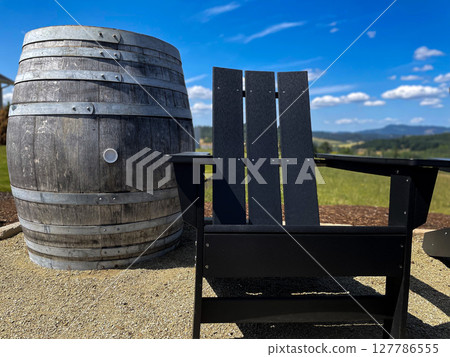 Rustic Barrel and Adirondack Chair in Scenic Vineyard Setting 127786555