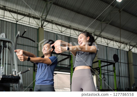 Fitness Friends. Two friends stretching together at the gym, promoting teamwork and health. Fitness Friends. Two friends stretching together at the gym, promoting teamwork and health. 127786558