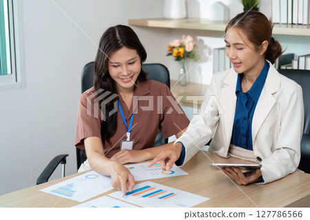Collaboration in Business. Two women analyzing data charts in a modern office. Collaboration in Business. Two women analyzing data charts in a modern office. 127786566