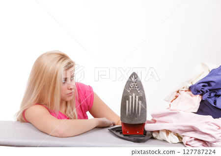 Woman holding iron about to do ironing 127787224