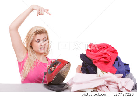 Bored woman pointing at clothes to iron 127787226