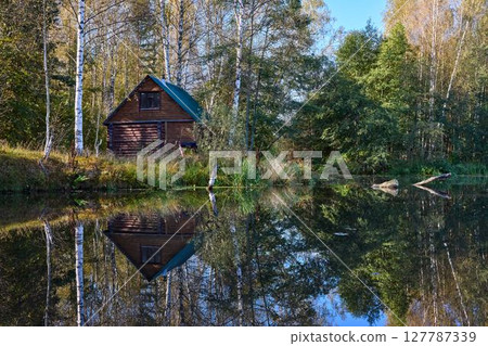 Tranquil Reflections: House and Trees Mirrored in River Tranquil Reflections: House and Trees Mirrored in River 127787339