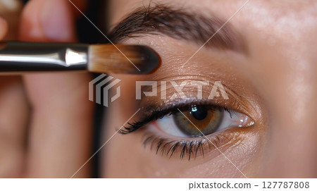 A makeup artist skillfully applies eye shadow, showcasing delicate precision and artistry. A makeup artist skillfully applies eye shadow, showcasing delicate precision and artistry. 127787808