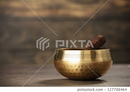 Golden Singing Bowl for Meditation on Rustic Background 127788464