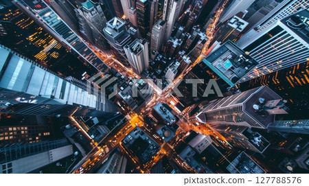 An aerial shot captures a bustling city at dusk, skyscrapers casting shadows, streets glowing with traffic. 127788576