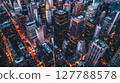 Aerial shot of a bustling cityscape at dusk: skyscrapers, shadows, vibrant city lights, dynamic urban energy. 127788578